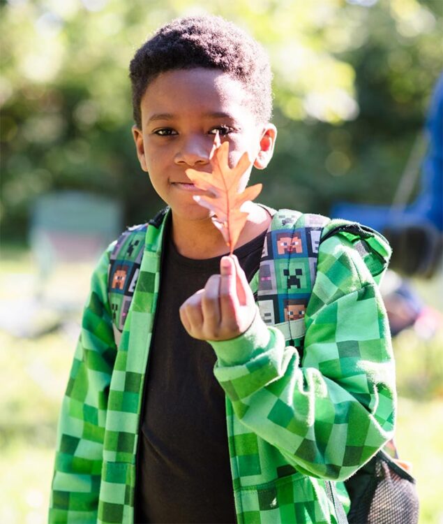 A boy holds up an orange leaf during an It's a W.I.N. event