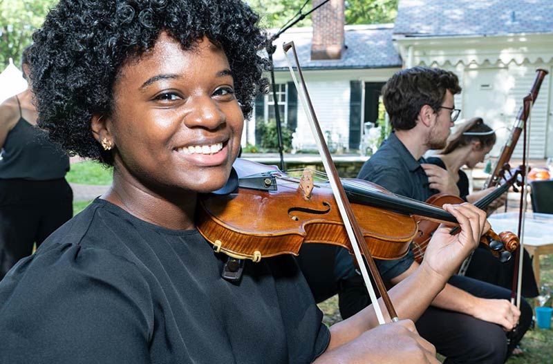 A girl smiling while playing the violin