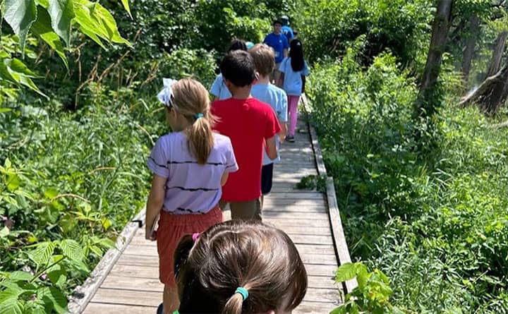 Kids walking down a planked path through the woods