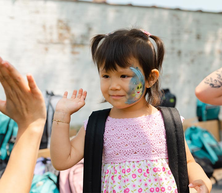 A young girl giving a high five after getting her explorer backpack from Brushwood