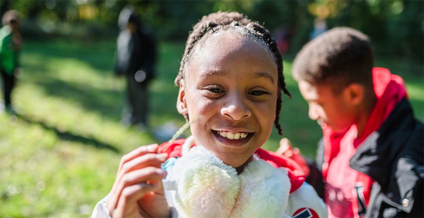 A girl holding up a blade of grass found at a Brushwood Center field trip in Lake County