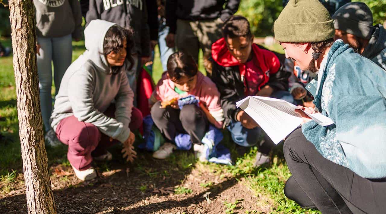 Kids gather around Dani Abboud to explore plants and leaves at a Brushwood Center field trip in Lake County