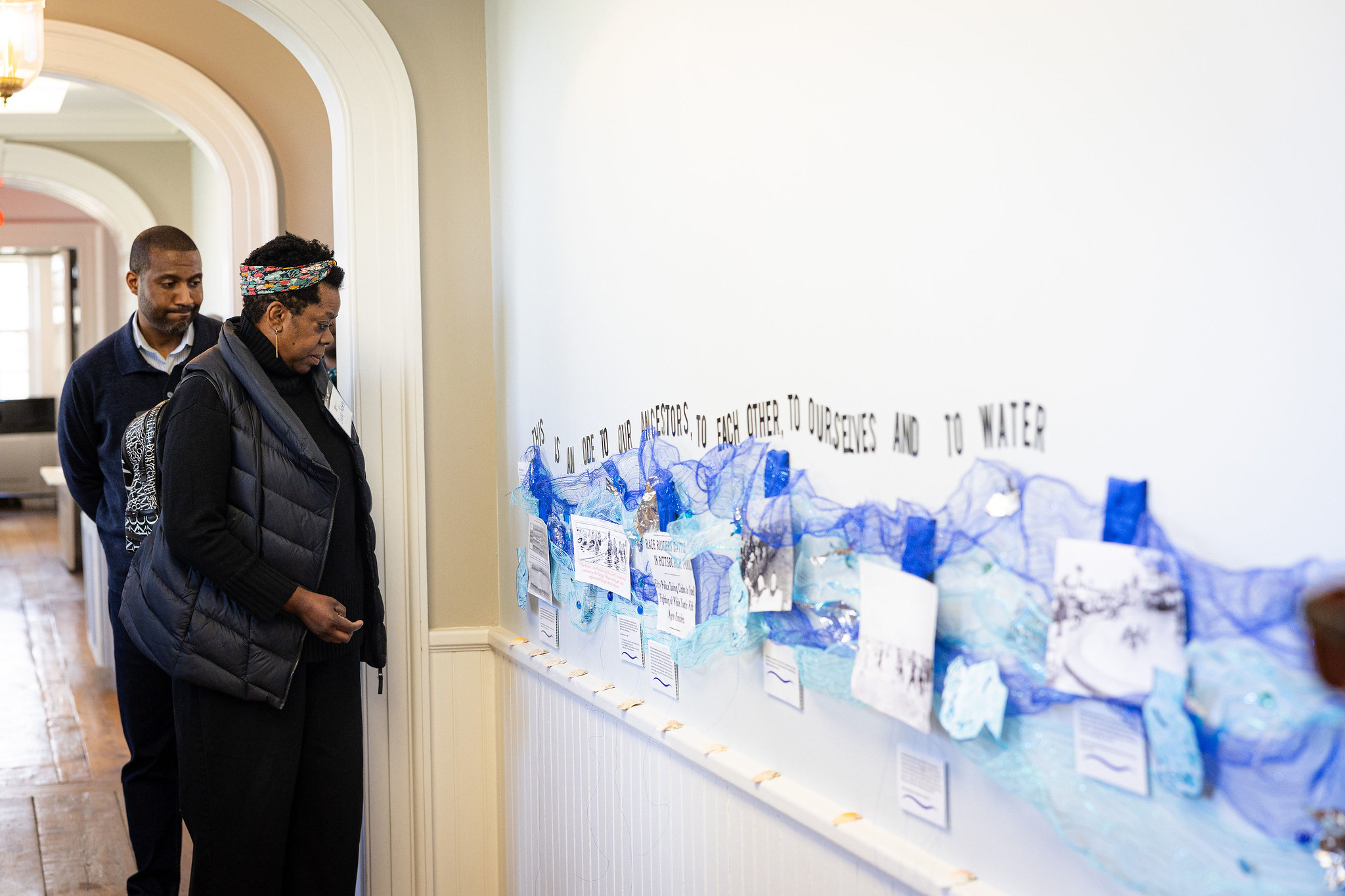 Two people view a piece of art that stretches down Brushwood Center's hallway.