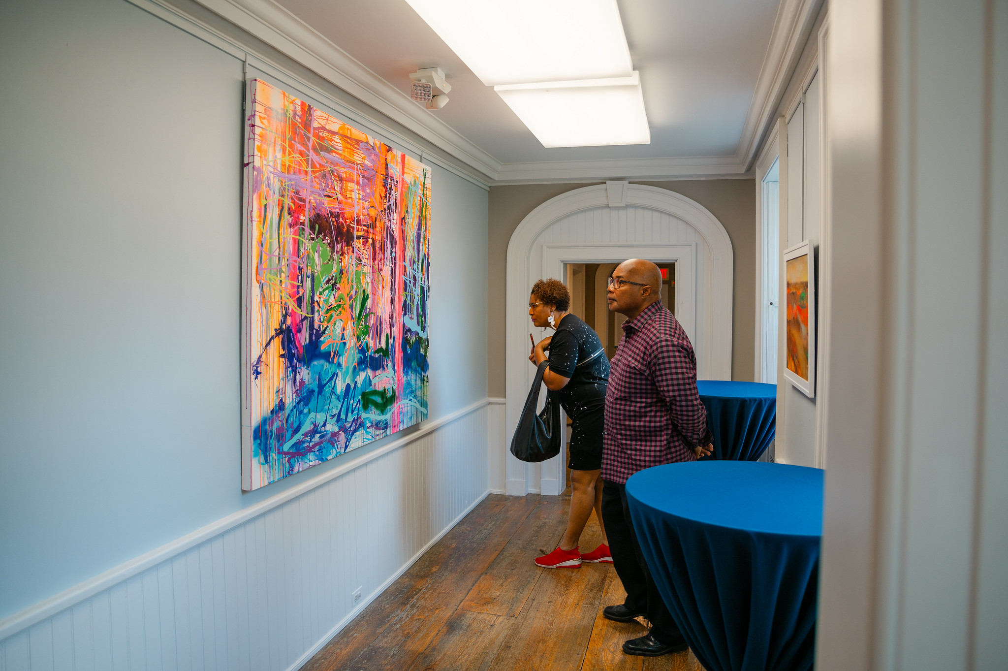 Two people look at a large colorful abstract painting at Brushwood Center