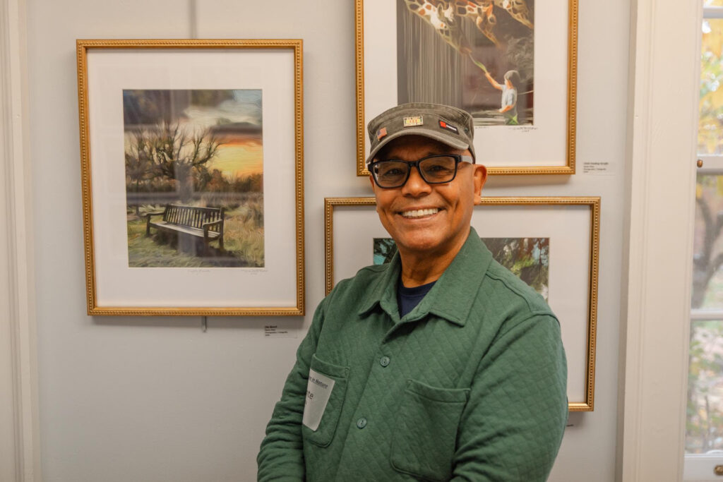 Dante Plata, Army Veteran, with his photography pieces at the At Ease in Nature opening.