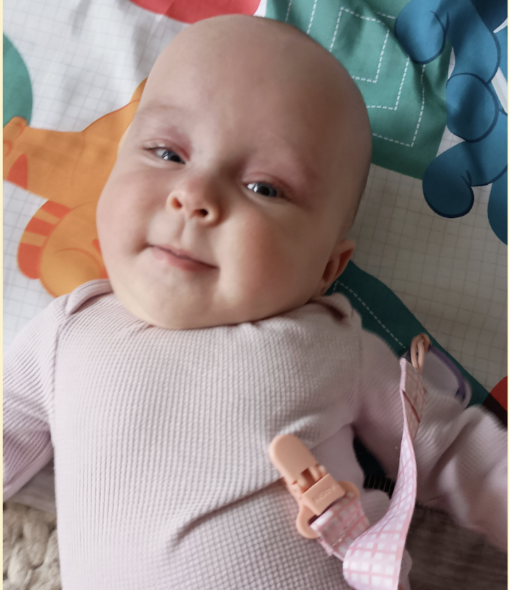A baby smiles up at the camera