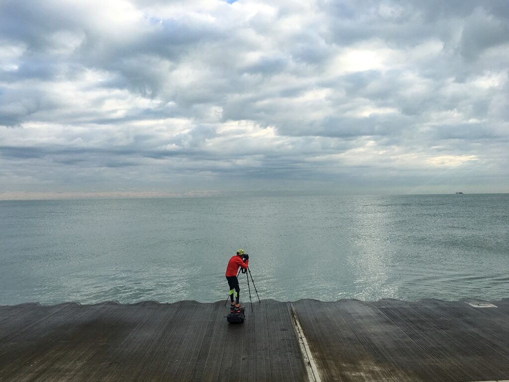 Lincoln Schatz with camera on shore of Lake Michigan