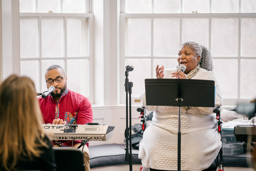 Angela Walker speaks while Tranelle Duffy plays the keyboard