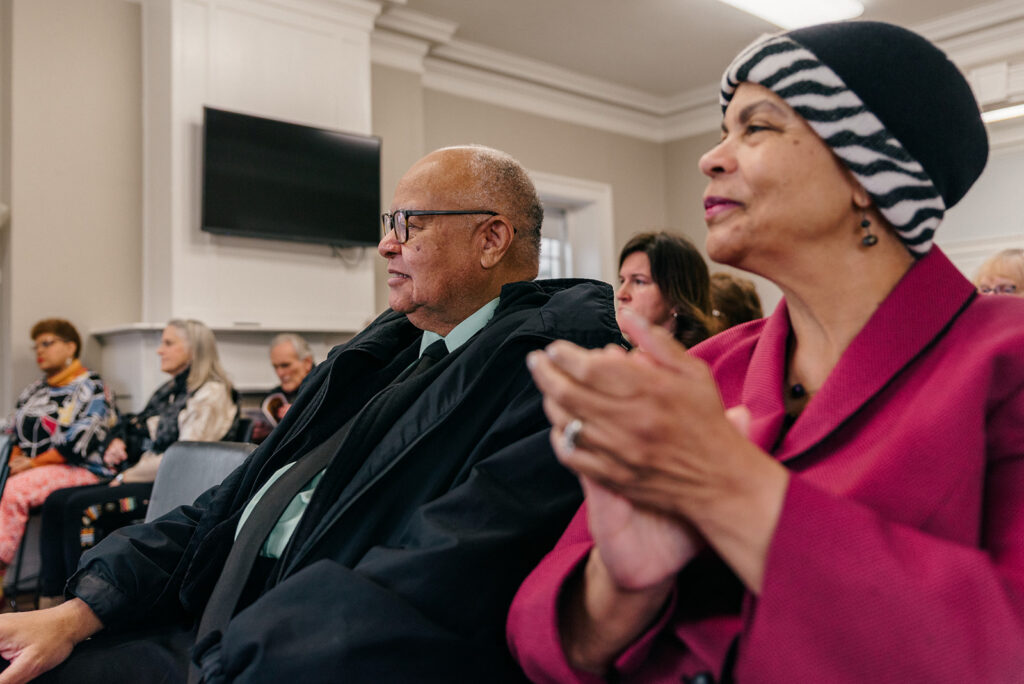 Audience members clap and smile