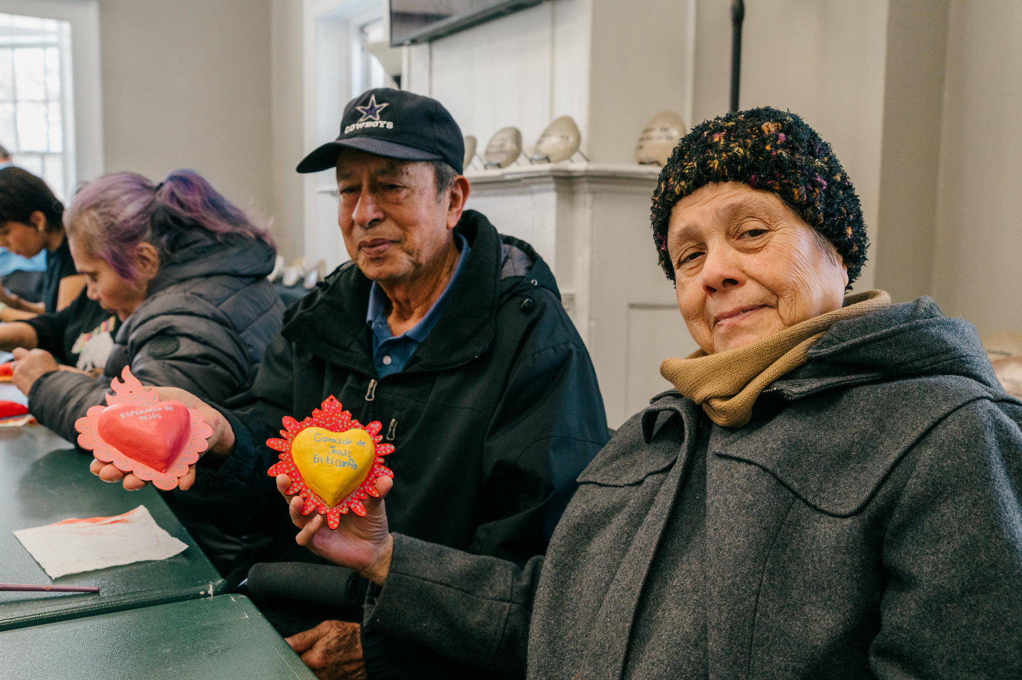 Two TIERRA community members show their artwork to the camera.