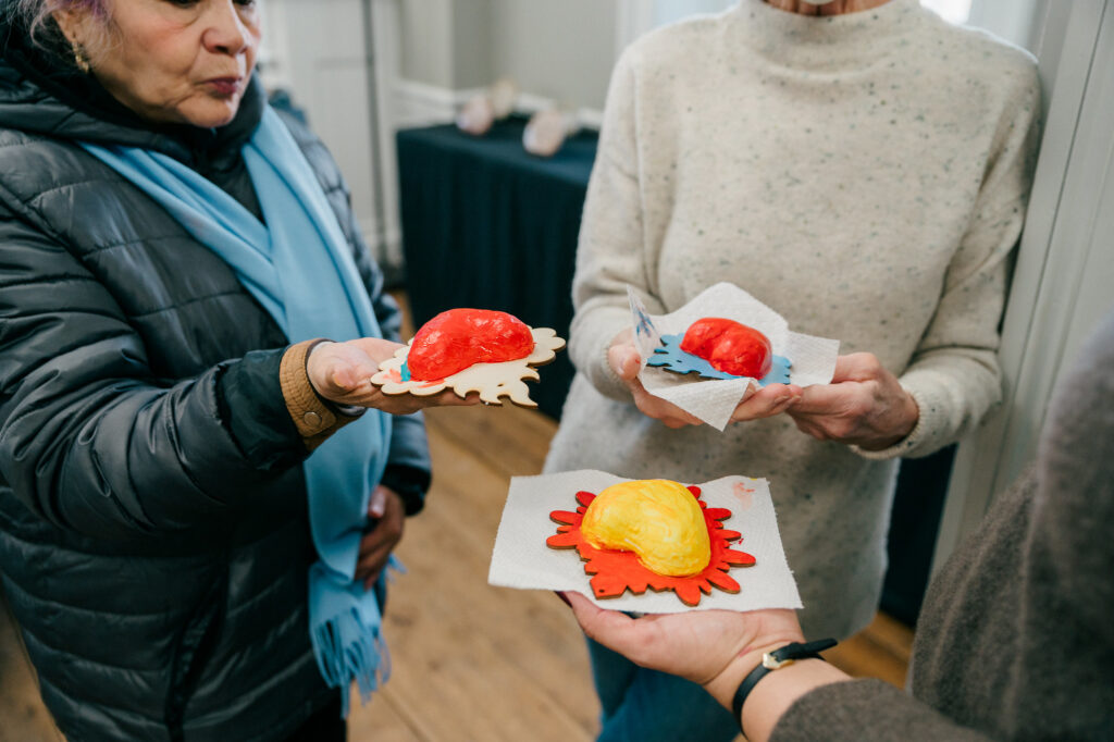 A group of three hold milagros hearts