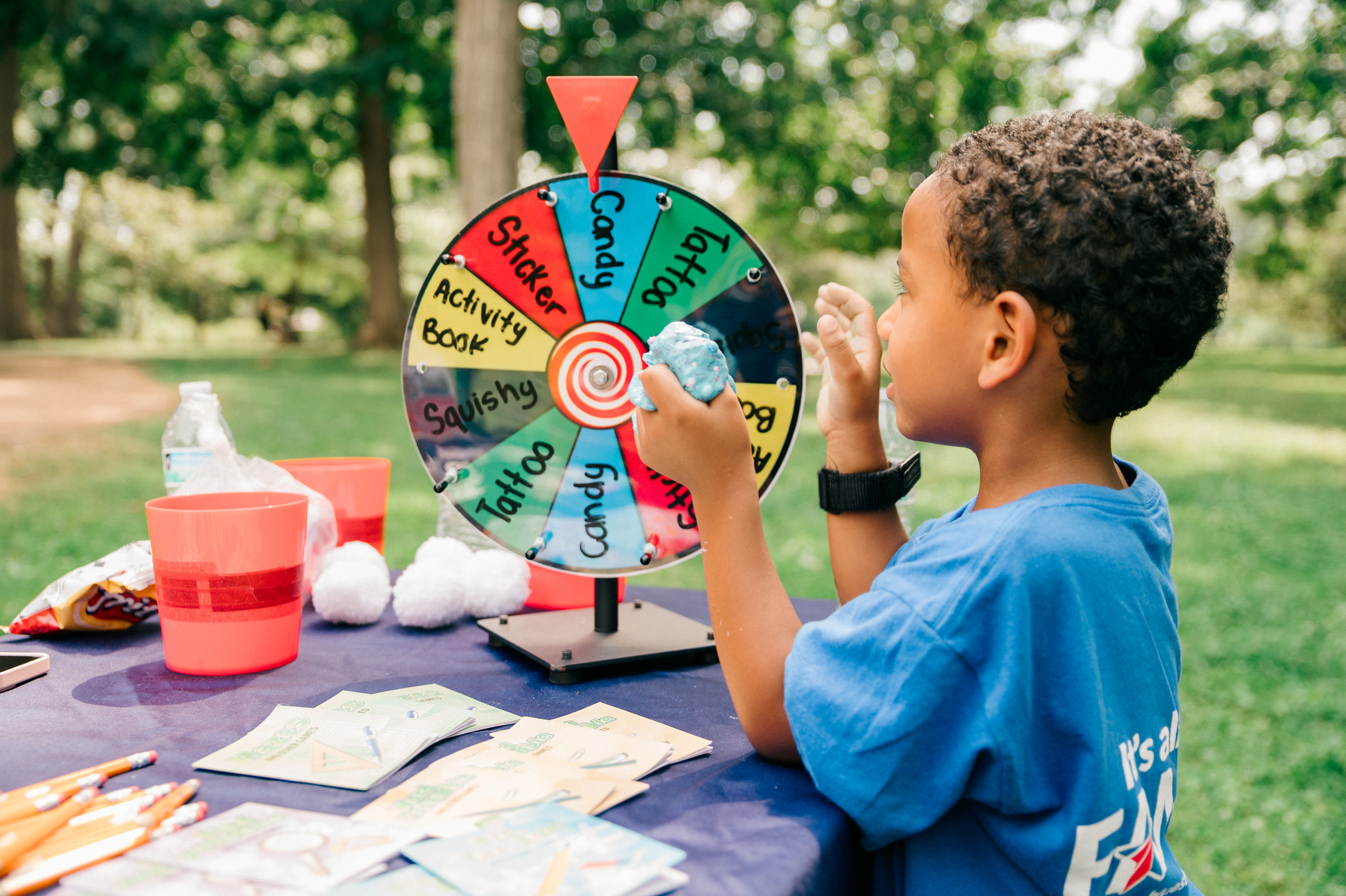 A child outside, next to a spinning wheel of prizes