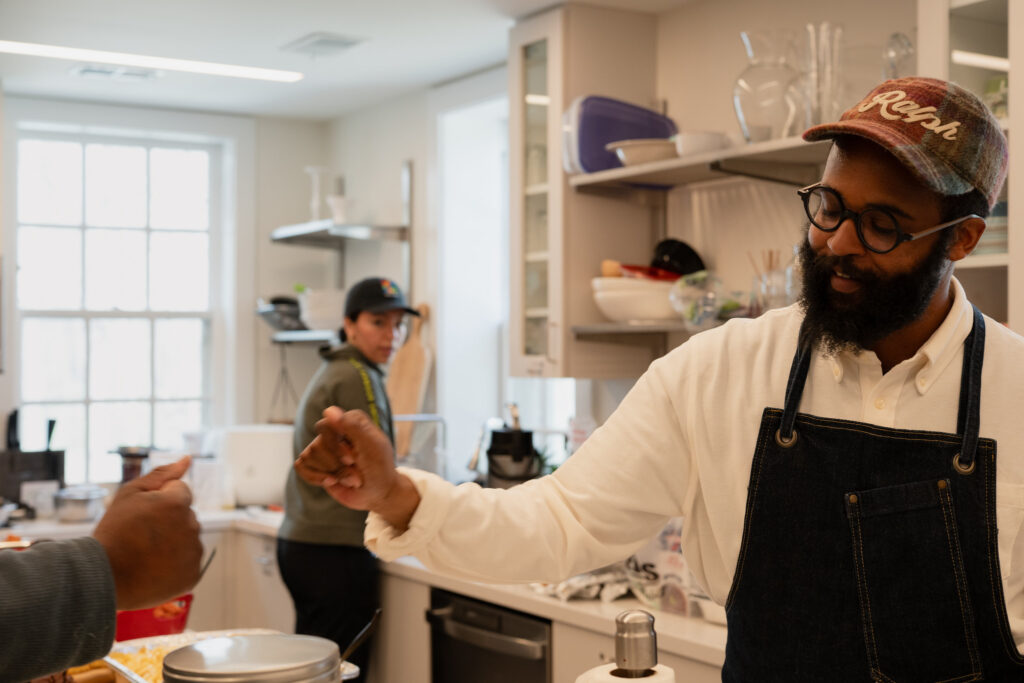 Chef Jeffrey Williams in the kitchen at Brushwood, fist-bumping a participant.